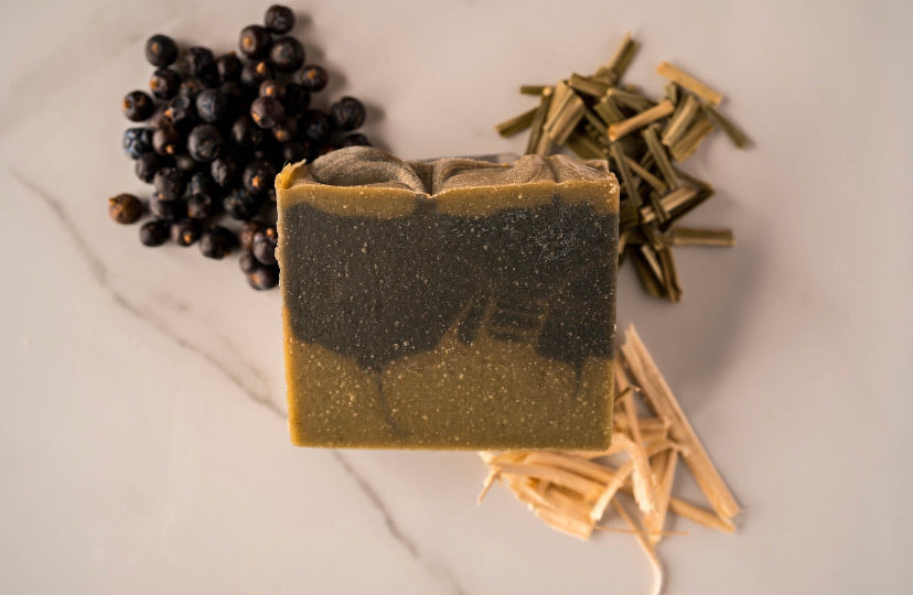 sweet wood soap. juniper berries decorate the upper left corner, lemongrass the top right and bottom right resr cedar shavings
