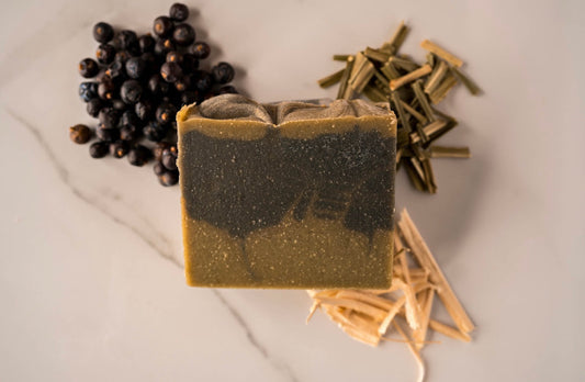 sweet wood soap. juniper berries decorate the upper left corner, lemongrass the top right and bottom right resr cedar shavings